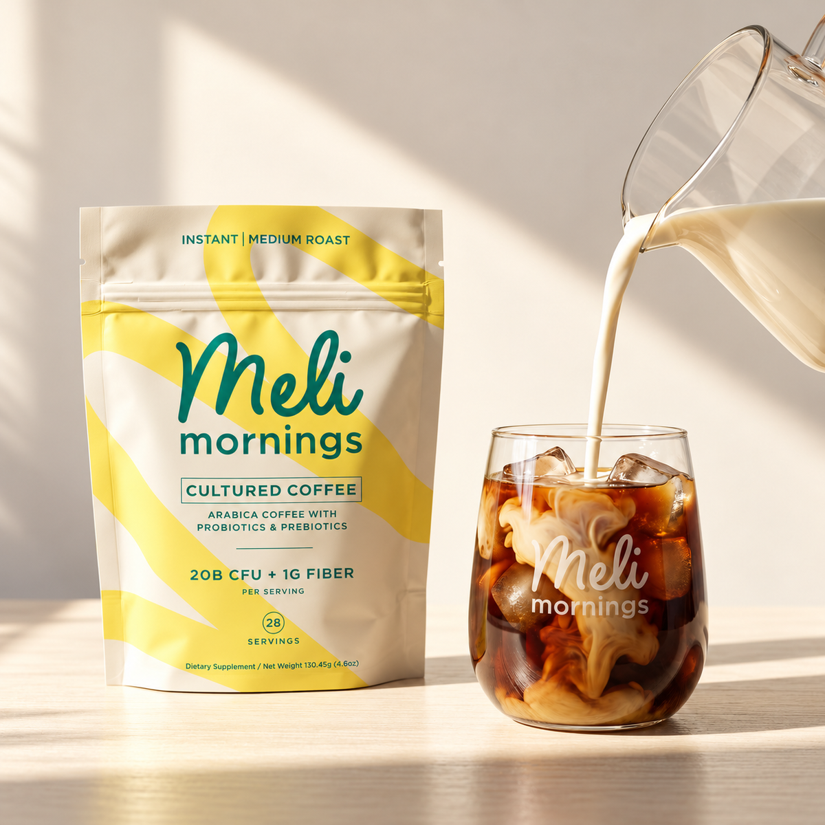 Meli Mornings Cultured Coffee pouch next to a glass of iced coffee with milk being poured in.